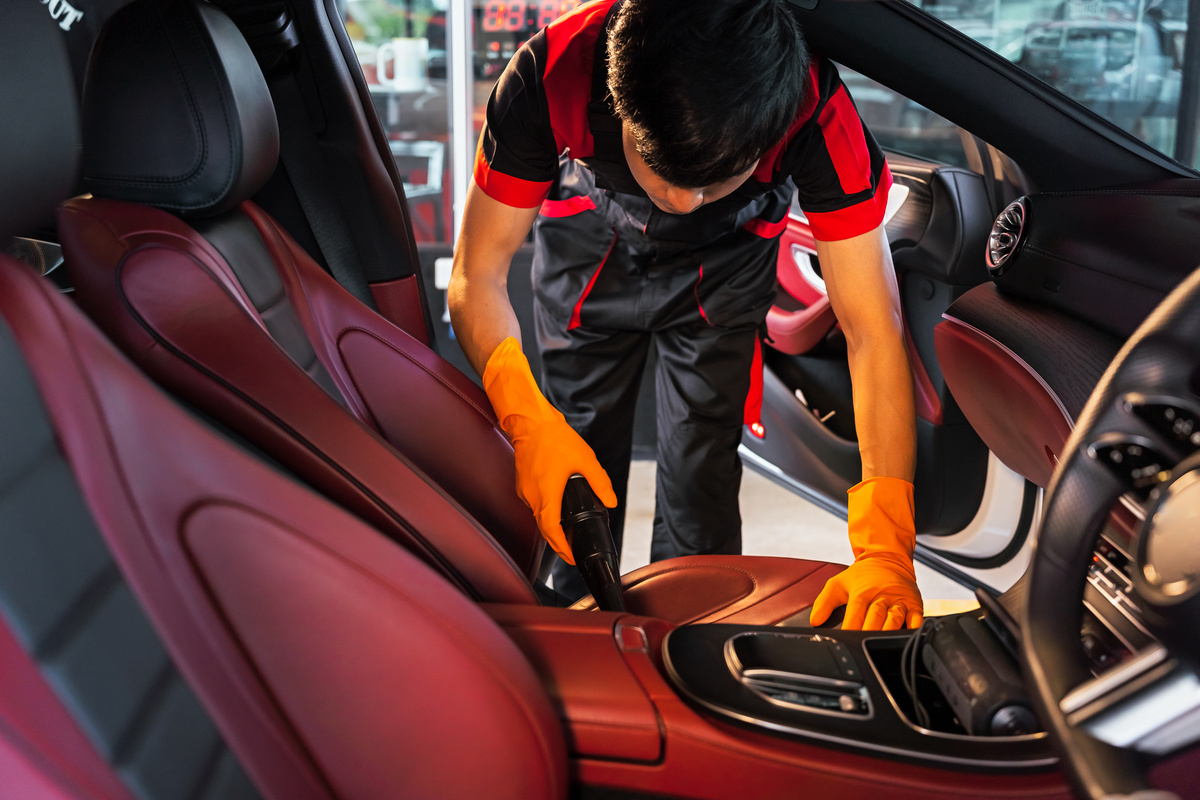 Car wash shop workers vacuuming, cleaning the car, cleaning the upholstery, cleaning the car console. Close-up shooting with in focus, partial sharpness of the image.